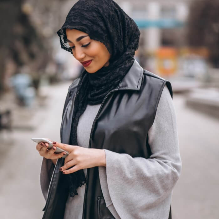 muslim woman using phone outside street